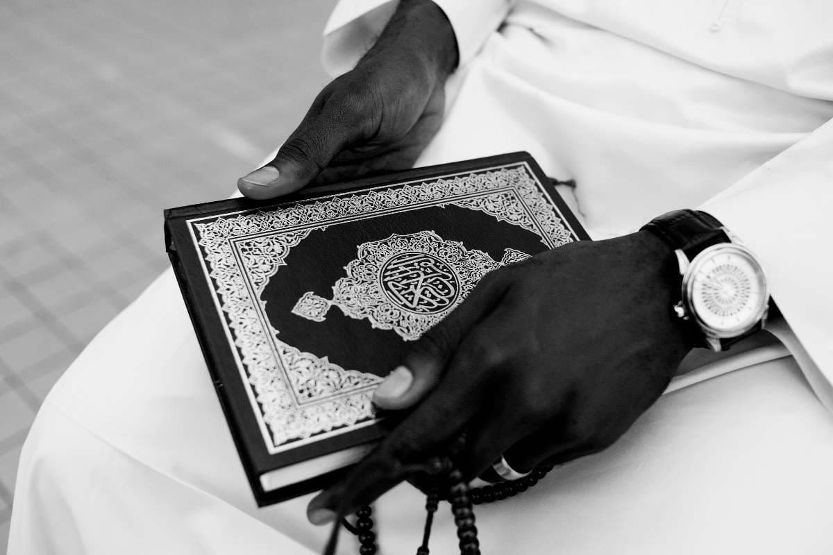 Musulman tenant le Coran et un chapelet, symbole de foi et de reflexion apres un reve de poule ou de coq